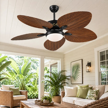 Tropical themed luxury hotel bedroom with a smart palm leaf ceiling fan light and panoramic ocean views.