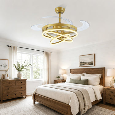 A modern bedroom with a gold ceiling fan light featuring white curved blades, shown installed in a bright, contemporary bedroom with a wooden bed, nightstands, and a window.