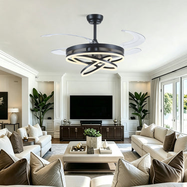 Modern ceiling fan light fixture with a black circular frame, glowing white LED rings, and three curved white blades, shown installed in a bright contemporary living room.